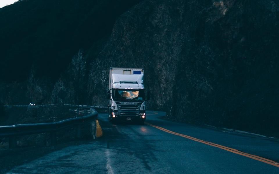A delivery truck driving along a mountain road at dusk