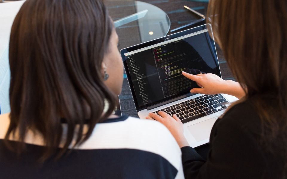 Two developers reviewing code together on a laptop