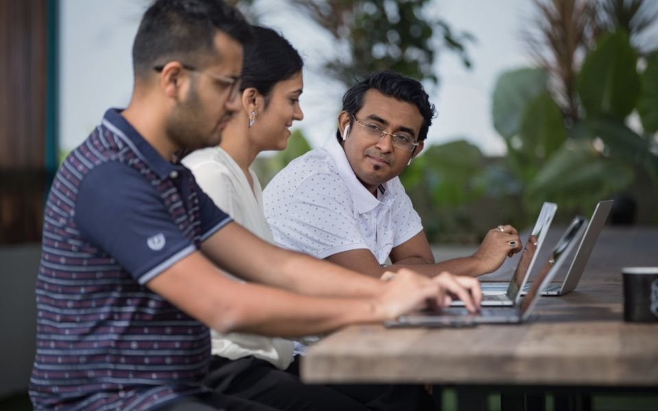Three developers working side by side on their laptops