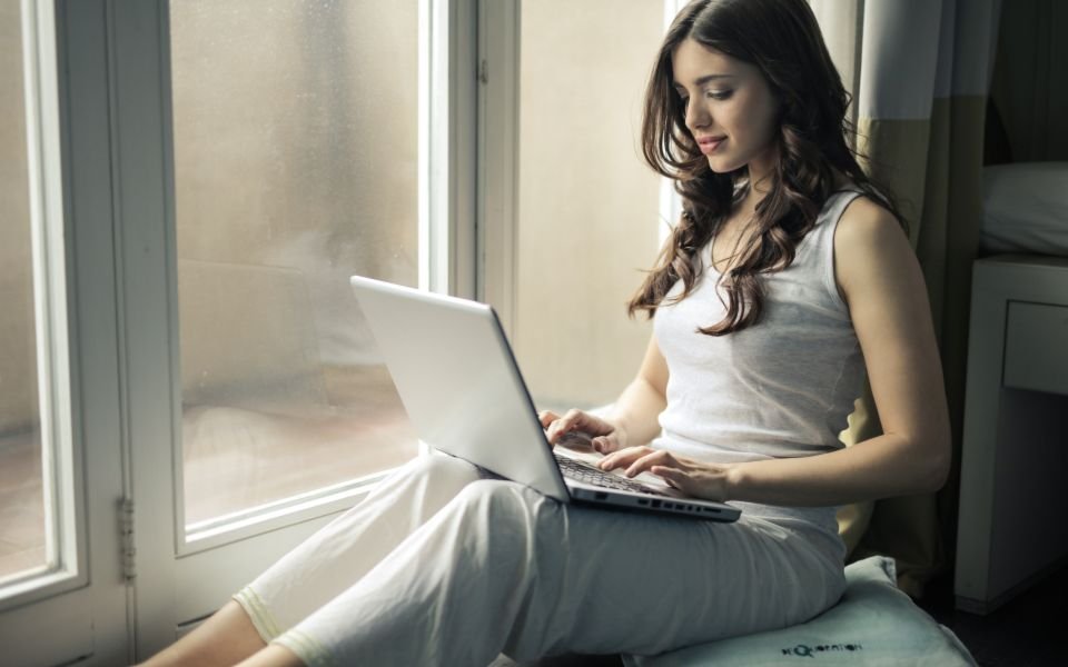 A woman working on her laptop by a bright window
