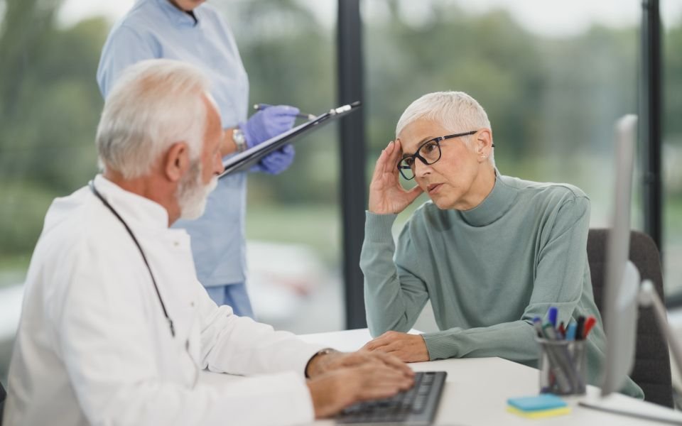 A doctor reviewing records on a computer with a patient