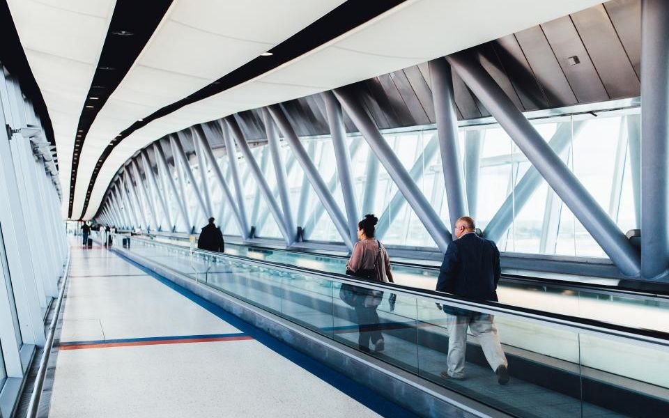 Travellers on a moving walkway in a bright airport terminal