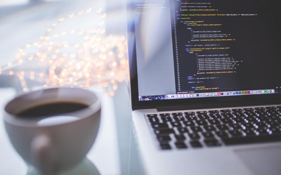 A laptop showing application code beside a cup of coffee, ready for a security review