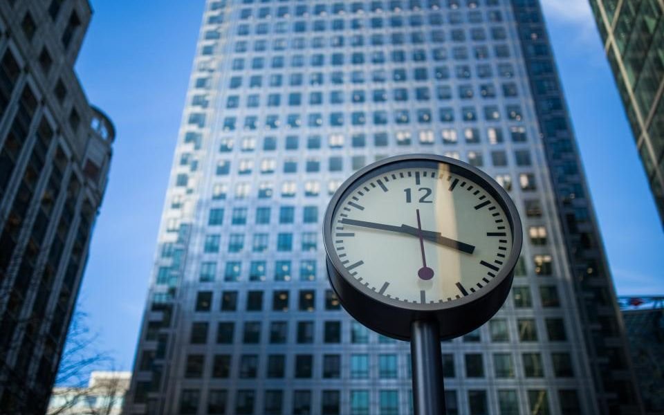 A clock in front of an office tower